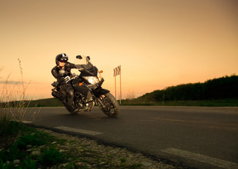 silhouette of rider on a motorbike driving at sunset - space for your text