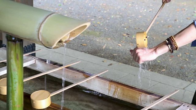 Young man who are visiting Japan is performing a cleansing ritual at the Meiji Jingu Shrine in Tokyo, Japan