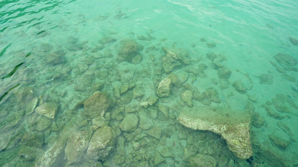 Turquoise shallow water surface and rocks stones on sea floor