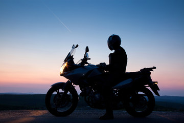 Plakat man on his motorbike admiring sunset - summer road trip - space for text