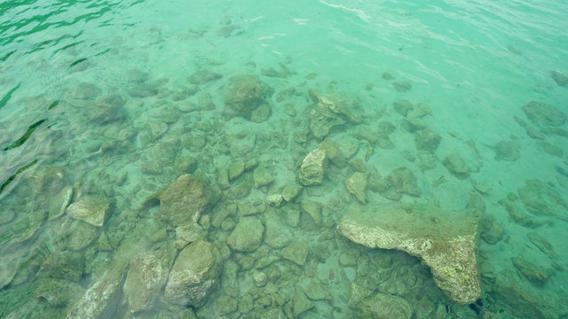 Turquoise Shallow Water Surface And Rocks Stones On Sea Floor