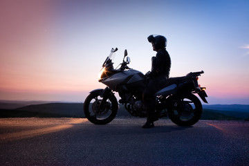 man on his motorbike admiring sunset - summer road trip - space for text