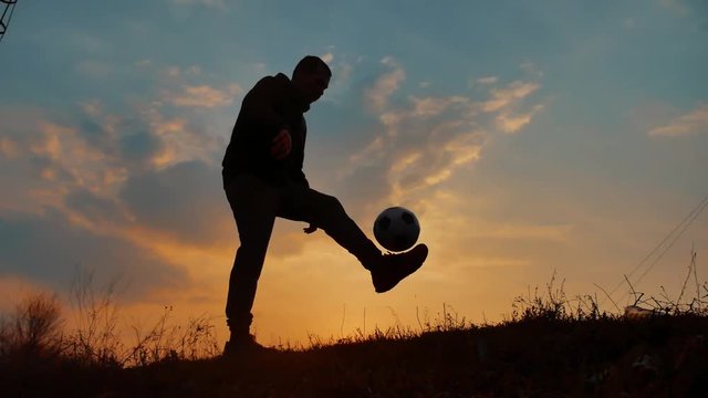 man coins a ball European the football soccer freestyle silhouette at sunset sunlight. man beats chasing ball football world championship lifestyle outdoors