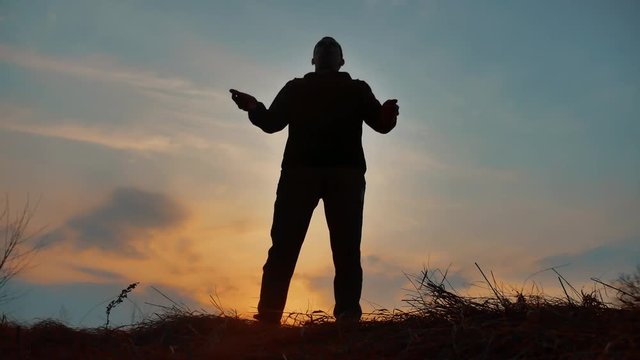 man warrior monk practicing silhouette karate kung Fu on the grassy horizon at sunset. Karate kick leg. Art of self-defense. Silhouette on a background of dramatic clouds at sunset lifestyle nature