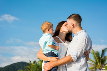 Happy Family are sweet kiss and hug on the beach While relaxing on weekends with blur sea background in travel and holiday concept.