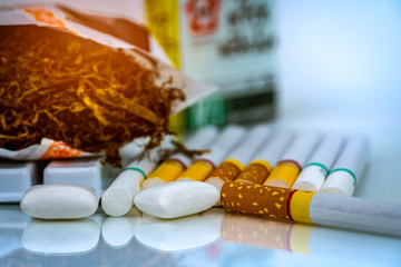 Nicotine chewing gum near pile of cigarettes and tobacco on white background with space. Quit smoking or smoking cessation and lung cancer concept. 31 May : World no tobacco day.