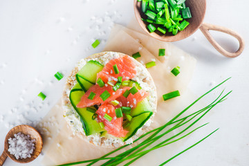 Crisp bread healthy snack with salmon, cottage cheese, cucumber stripes, scallion and sea salt. Easy breakfast concept close-up with copy space.