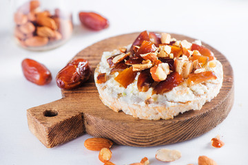 Healthy snack with crisp bread, dates, soft creme cheese, almond and nuts. Easy breakfast close-up on a white background with copy space.
