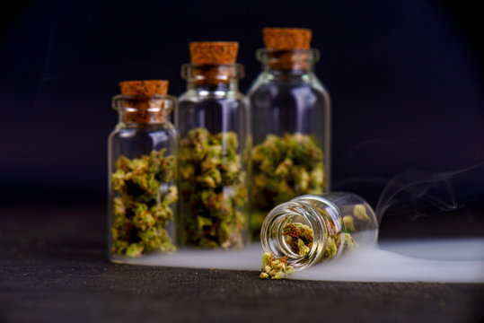 Detail of assorted jars with cannabis calyxes (sour tangie strain) isolated on black