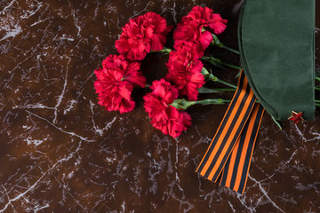 red flowers, military cap with a red star lie on a marble slab