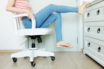 Portrait People Sit. Woman in Fashion Striped Orange Shirt and Lack Blue Jeans. Beautiful Female Sitting on White Chair at Home Background