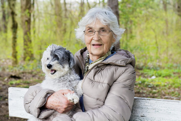 Happy Smiling Senior Woman Hugging her Poodle Dog in a Spring Park