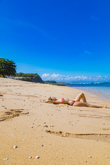 Fototapeta na wymiar Female lying on a sandy beach near the ocean / sea water.