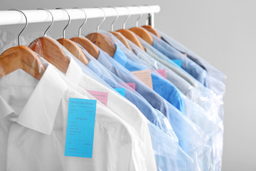 Rack with clean clothes on hangers after dry-cleaning against light background © New Africa
