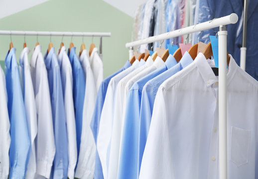 Racks with clean clothes on hangers after dry-cleaning indoors