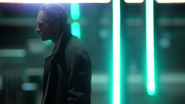 4k Lonely man wit coat walking and thinking at the night street with neon light background of city