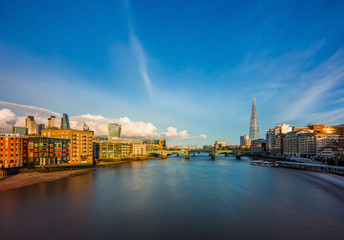 London, England - Panoramic skyline view of central London with skyscrapers of Bank district, sightseeing boat on River Thames, Tower Bridge and other famous landmarks at sunset