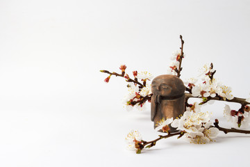 Figurine of a Buddhist monk and a branch of a cherry tree with flowers on a light background. Concept of spring and Chinese New Year.