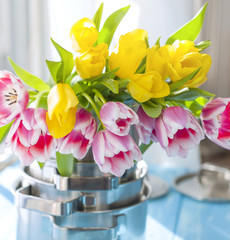 A bouquet of spring tulips of yellow and pink color. The flowers in new saucepans. Dishes. Card. Gift