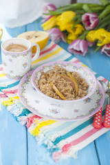 a cup of fragrant coffee and porridge with a quince. A healthy and delicious breakfast. A bouquet of spring bright tulips. Blue wood background. Free method for text
