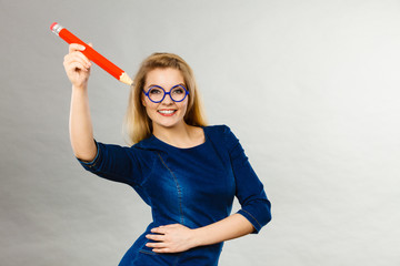 Smiling woman holds big pencil in hand