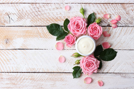  a care cream in a jar on a wooden background with beautiful roses. anti-aging cream. Cream for skin care. for hands. for face. cosmetics for care. 