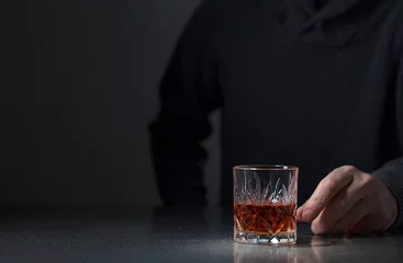 Fotobehang Man's hand reaches for a glass of alcohol. © Igor Normann