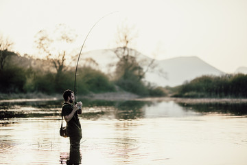 Fisherman in the lake at sunset