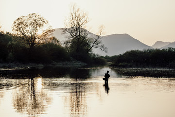 Fototapeta na wymiar Fisherman in the lake at sunset