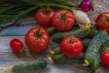 Cucumbers and tomatoes on a light table in a rustic style. Fresh vegetables from the greenhouse.