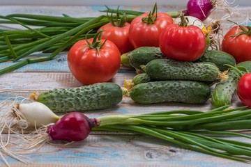 Cucumbers and tomatoes on a light table in a rustic style. Fresh vegetables from the greenhouse.