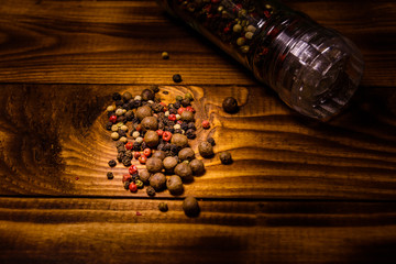 Pepper mill and scattered spices on the wooden table