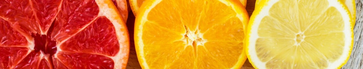 Banner of Sliced fresh lemons, grapefruits, oranges on a wooden cutting board with a knife