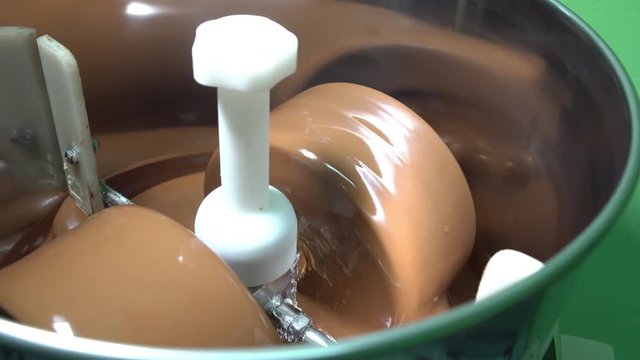 A conching machine keeps chocolate liquid. Chocolate turning in a steel bowl