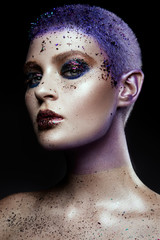 Portrait of beautiful woman with sparkles on her face. Girl with art make up in color light. Fashion model with colorful make-up