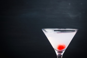 Bitter cocktail with sweet cherry in martini glass. Selective focus.