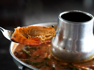 Thai traditional menu call Tom Yum Kung, spicy and sour soup with shrimps serving on hot pot, close up view