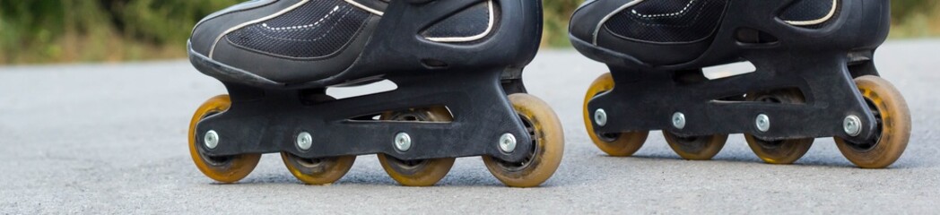 Banner of Young man in blue jeans riding roller skates in the city. Close up legs