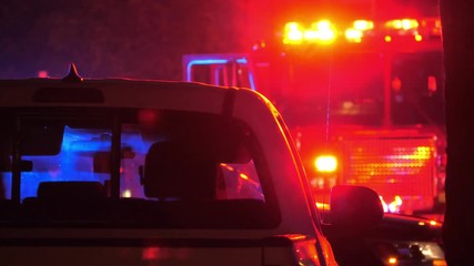 Flashing red  and blue emergency lights  seen through car's interior silhouette at night. Fire truck in background. 4K UHD.