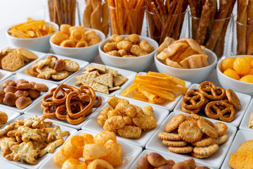 Rows of many types of savory snacks in white ceramic dishes.