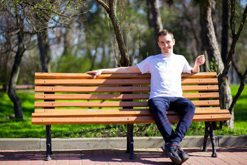 Handsome man walking in park and sits on bench and waiting for girlfriend. nature in Spring 