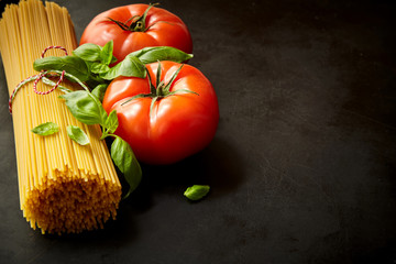 Naklejka na ściany i meble Bunch of spaghetti among tomatoes with basil
