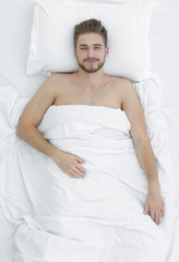 Obraz na płótnie Canvas the top view. smiling man lying on the bed