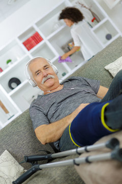 happy old man with crutches sitting on a sofa