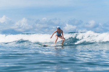 woman in swimming suit and cap surfing in ocean