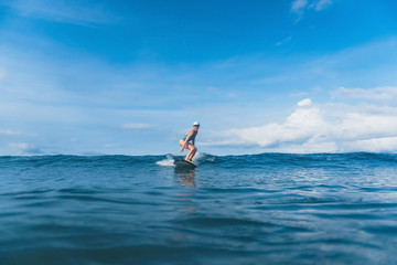 attractive woman in swimming suit surfing in ocean