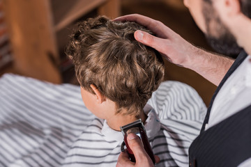 high angle view of barber cutting hair of little kid with Hair Clipper