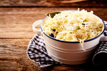 Bowl of sauerkraut in close up on wooden table - obrazy, fototapety, plakaty