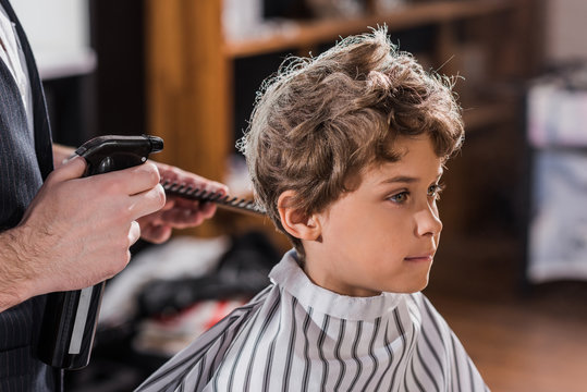 Cropped Shot Of Barber Spraying Hair Of Adorable Little Kid At Kids Barbershop