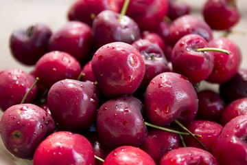 Ripe red cherries inside the transparency blue bowl on the table